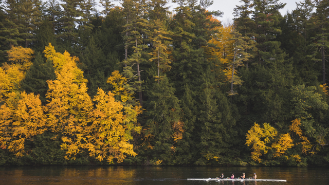 The Connecticut River with autumn trees and a crew boat on the water.